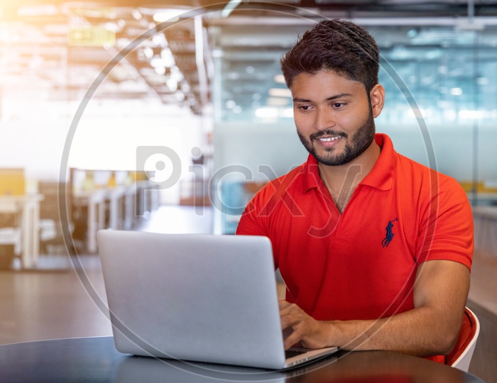 Indian Male student working on laptop