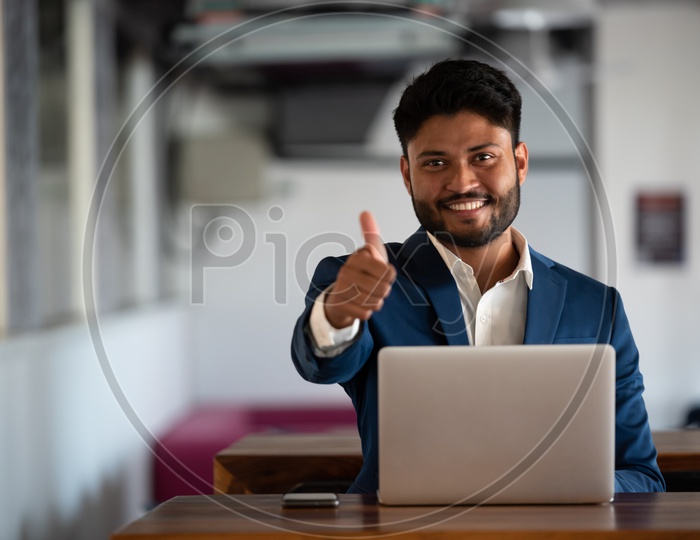 Successful Young Indian Businessman With Thumb up Gesture At Indoor Background