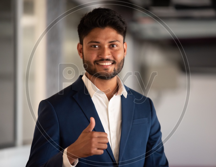 Successful Young Indian Businessman With Thumb up Gesture At Indoor Background