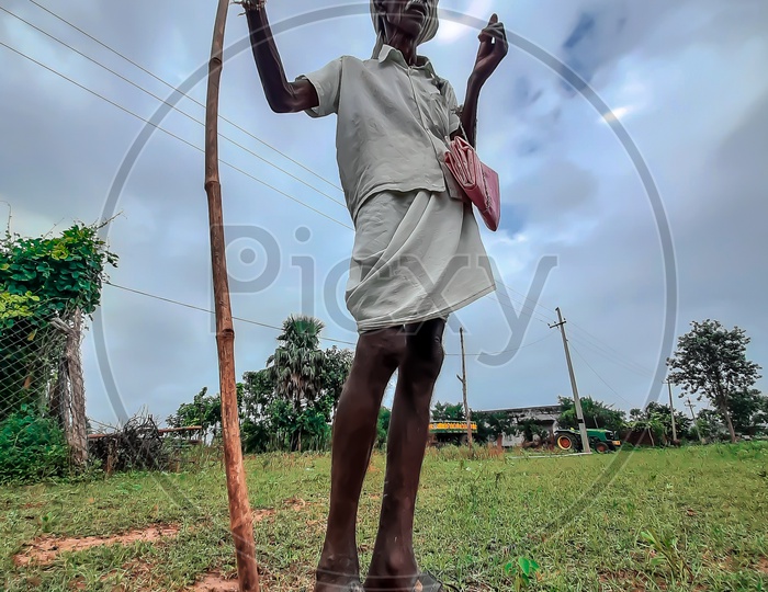 Indian Farmer Standing With Support Of a Stick