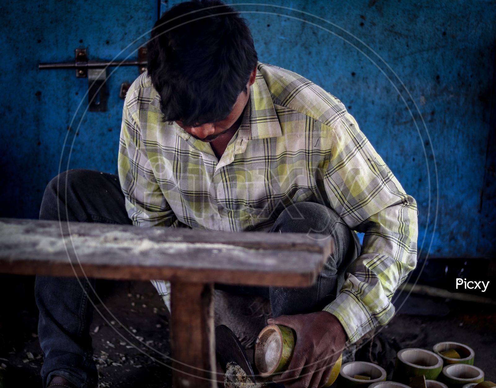 Worker Cutting Bamboo Wood Logs In an Workshop