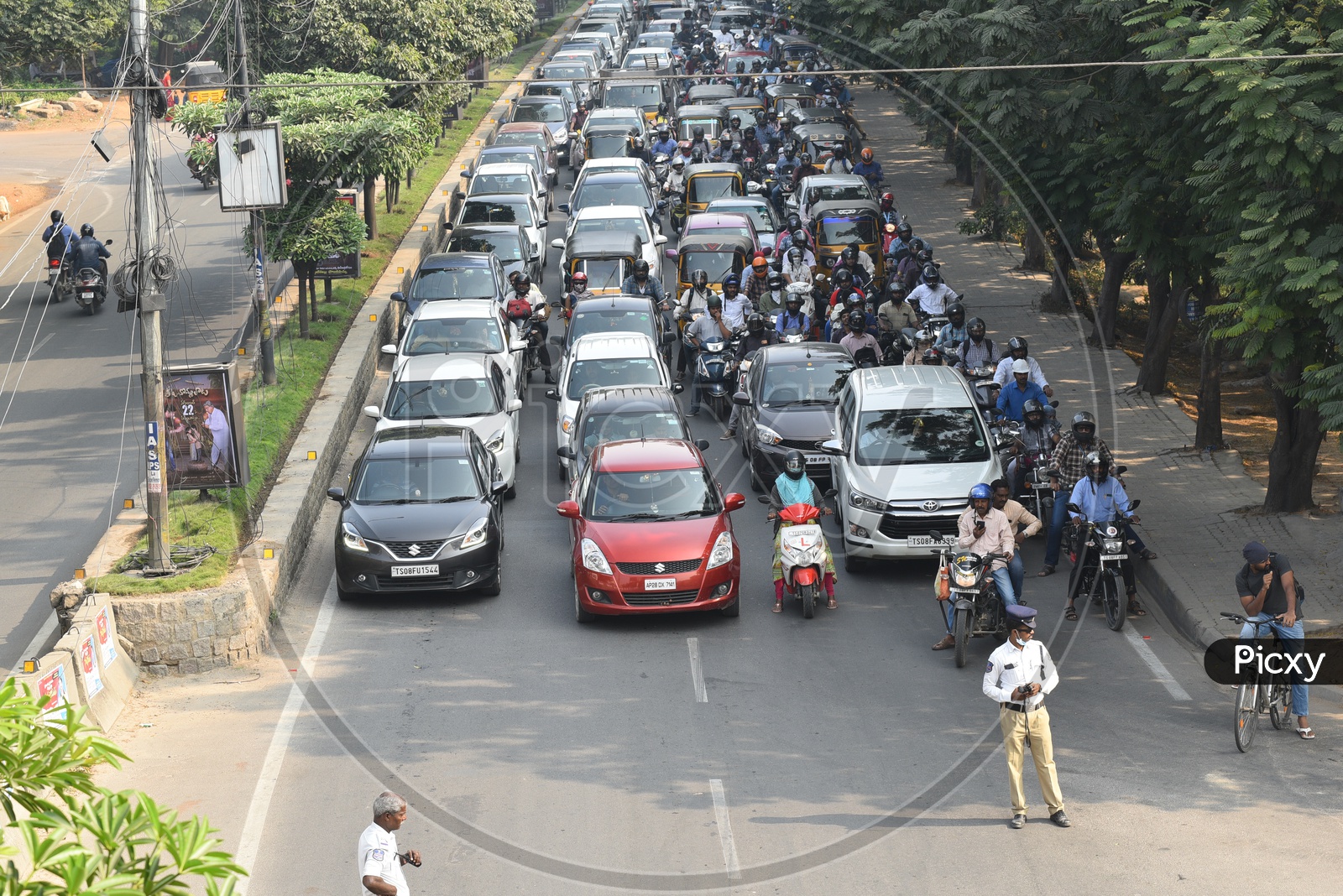 Traffic Police regulating Traffic  With Office Going Employees waiting in Cars And On Bikes