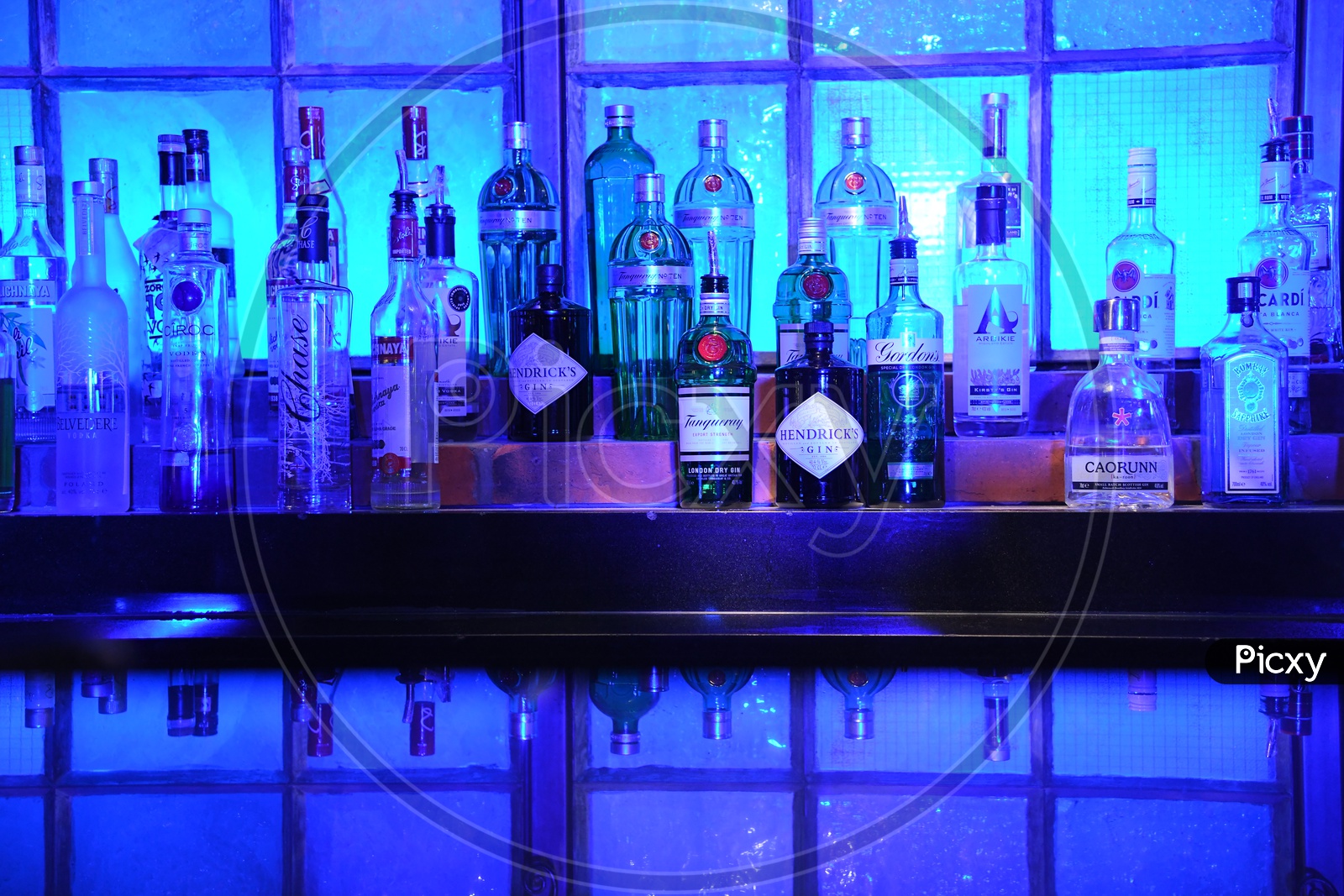 Alcohol Bottles On an Bar Counter With Neon Blue Light Ambiance