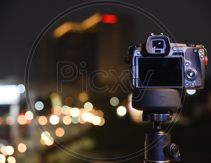DSLR Camera Mounted to a Tripod With Traffic Lights Bokeh Background