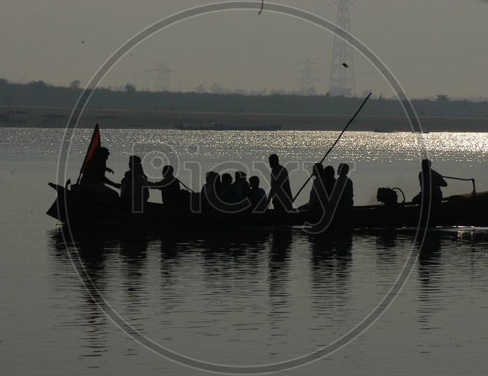 People on a Wooden Boat crossing the River