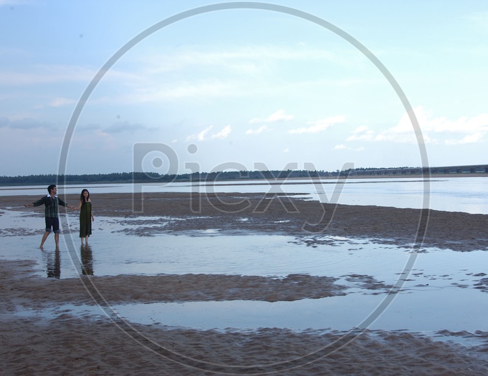 Indian Couple or Lovers Walking on Sand near a River