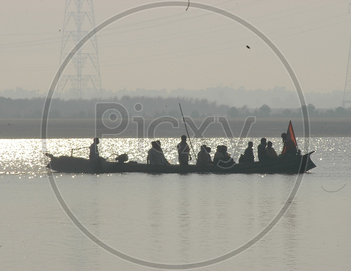 People on a Wooden Boat crossing the River