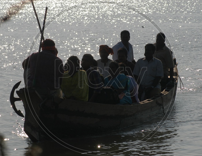 People in a Wooden Boat Crossing the River