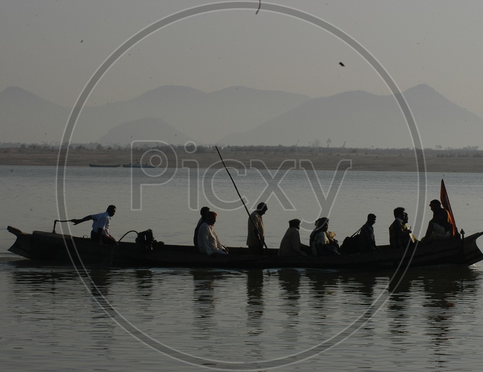 People in a Wooden Boat Crossing the River