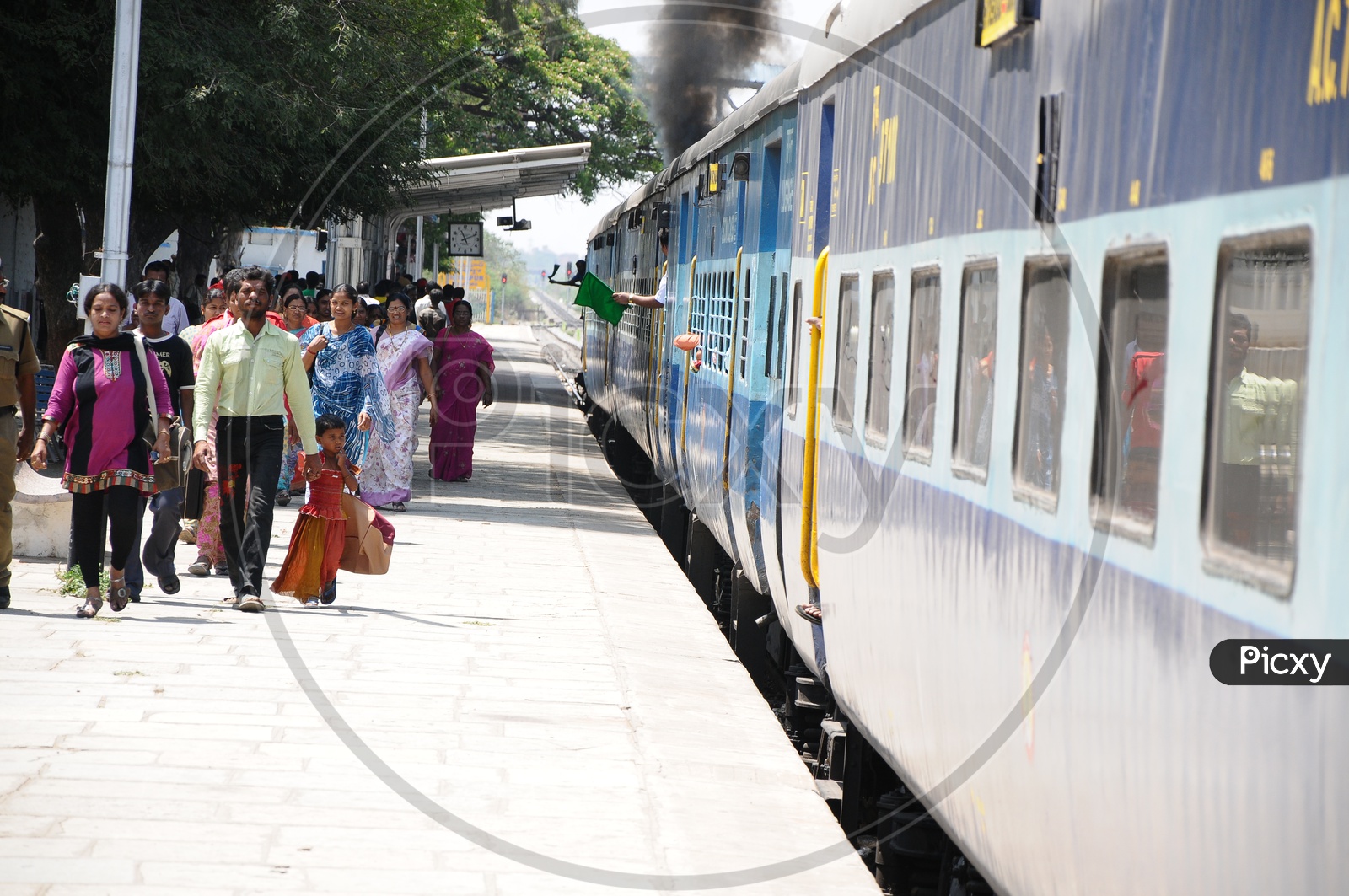 Passengers Walking on Railway Station Footpath With a Train Stranded on Platform
