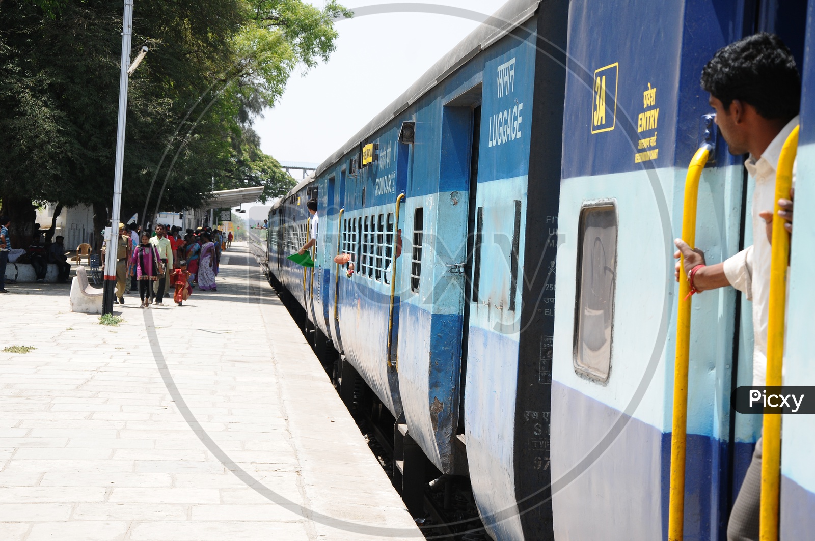 Passengers Walking on Railway Station Footpath With a Train Stranded on Platform