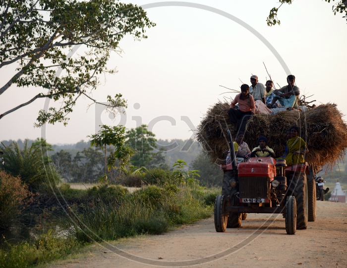 Tractor on The Rural Village Roads With People Siting on The Top