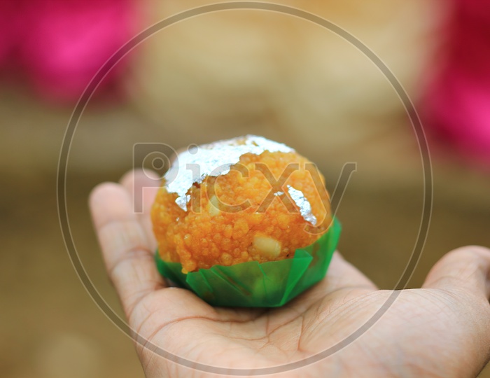 An Indian Sweet Laddoo In Hand With Selective Focus And Shallow Depth Of Field