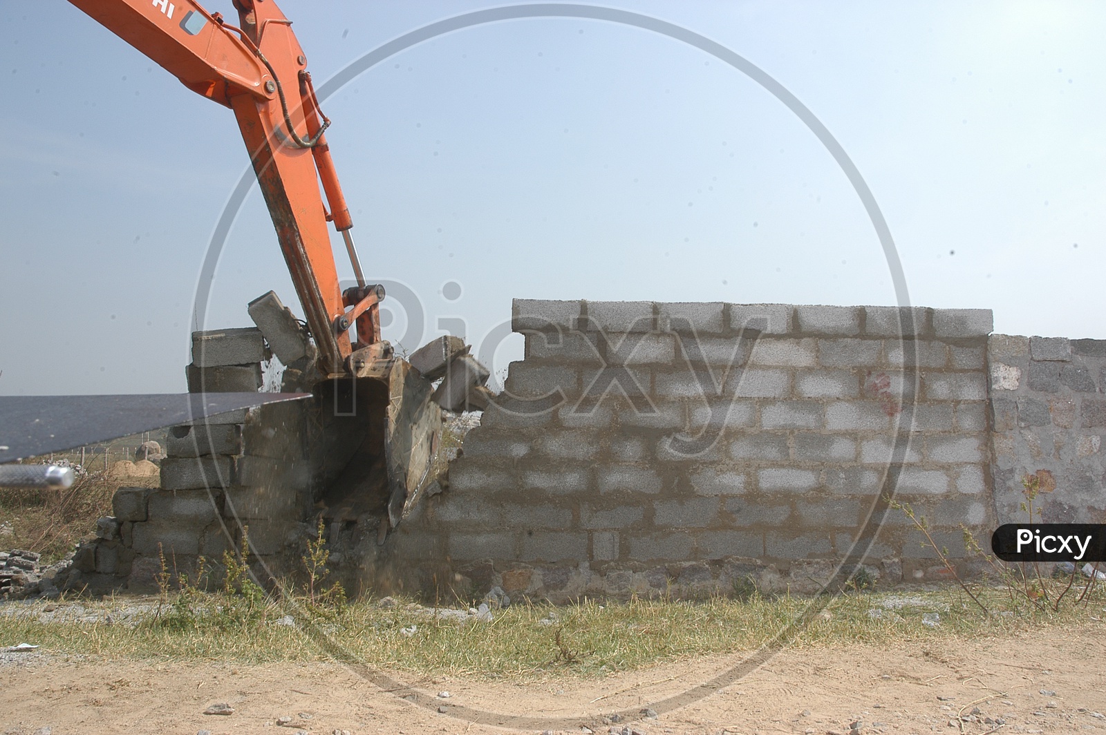 A Proclainer Demolishing Protective Walls around a Vacant Land