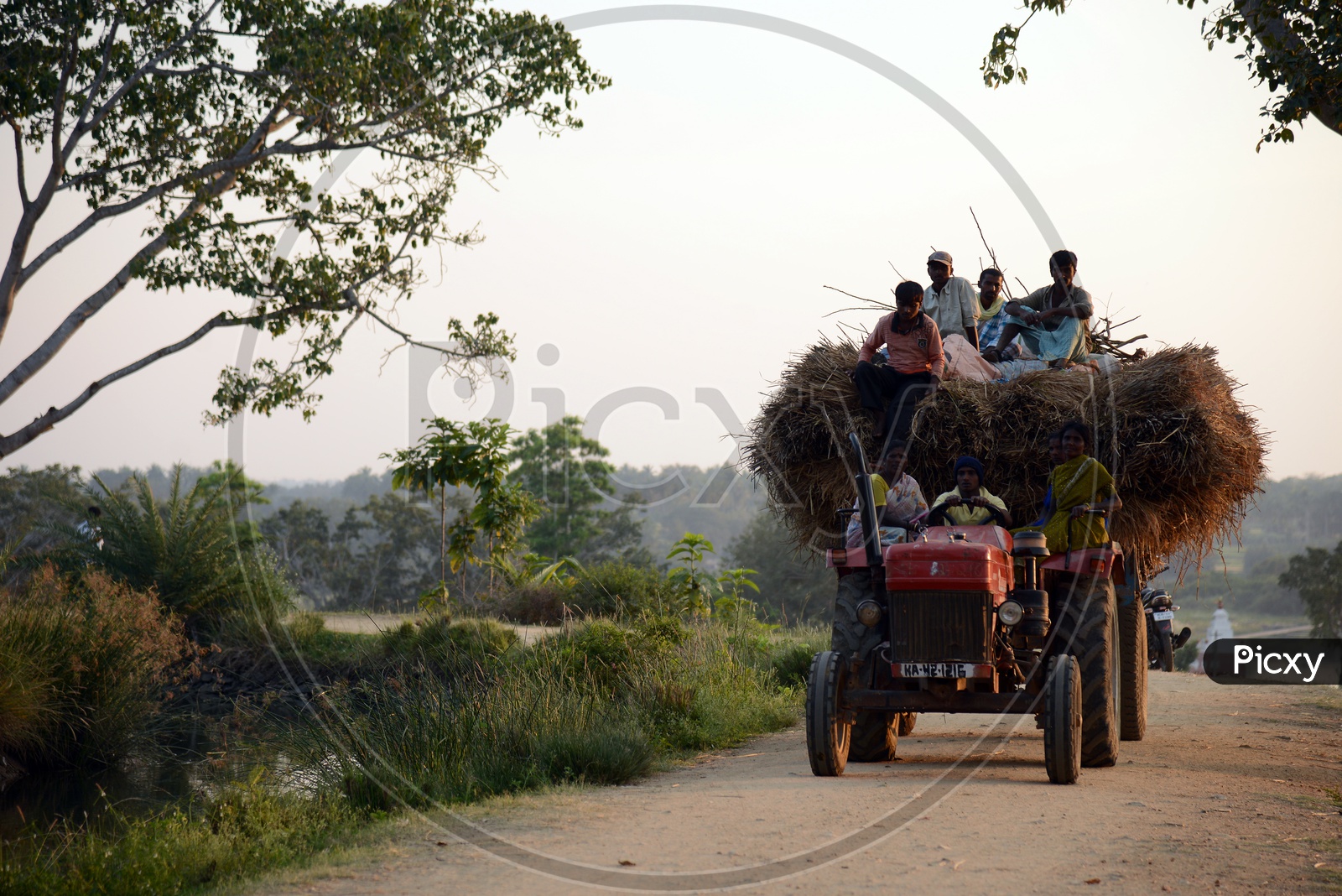 Tractor on The Rural Village Roads With People Siting on The Top