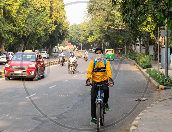 A man riding bicycle, covering his face with handkerchief to avoid pollution
