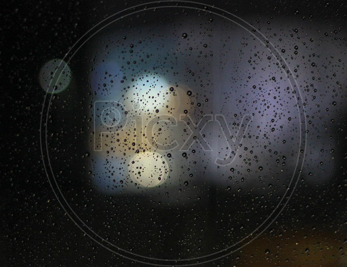 Water Droplets On A Glass Surface With Bokeh Lights In Background