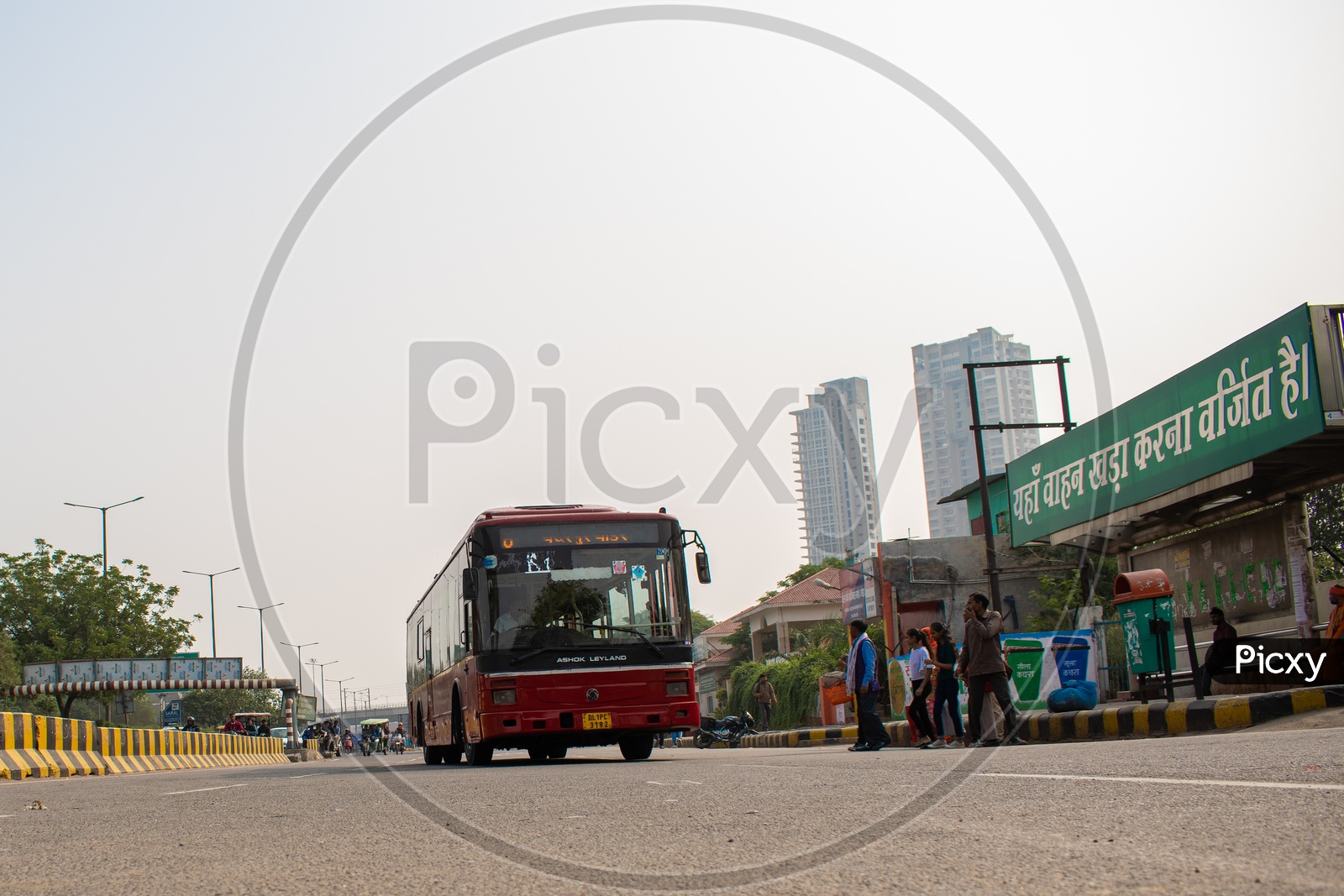 DTC AC red color bus at a bus stop and passengers waiting to get into the bus