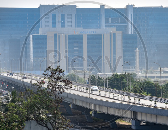 Vehicles on Flyover at Raheja Mindspace, Hyderabad. Novartis office in the backdrop. 