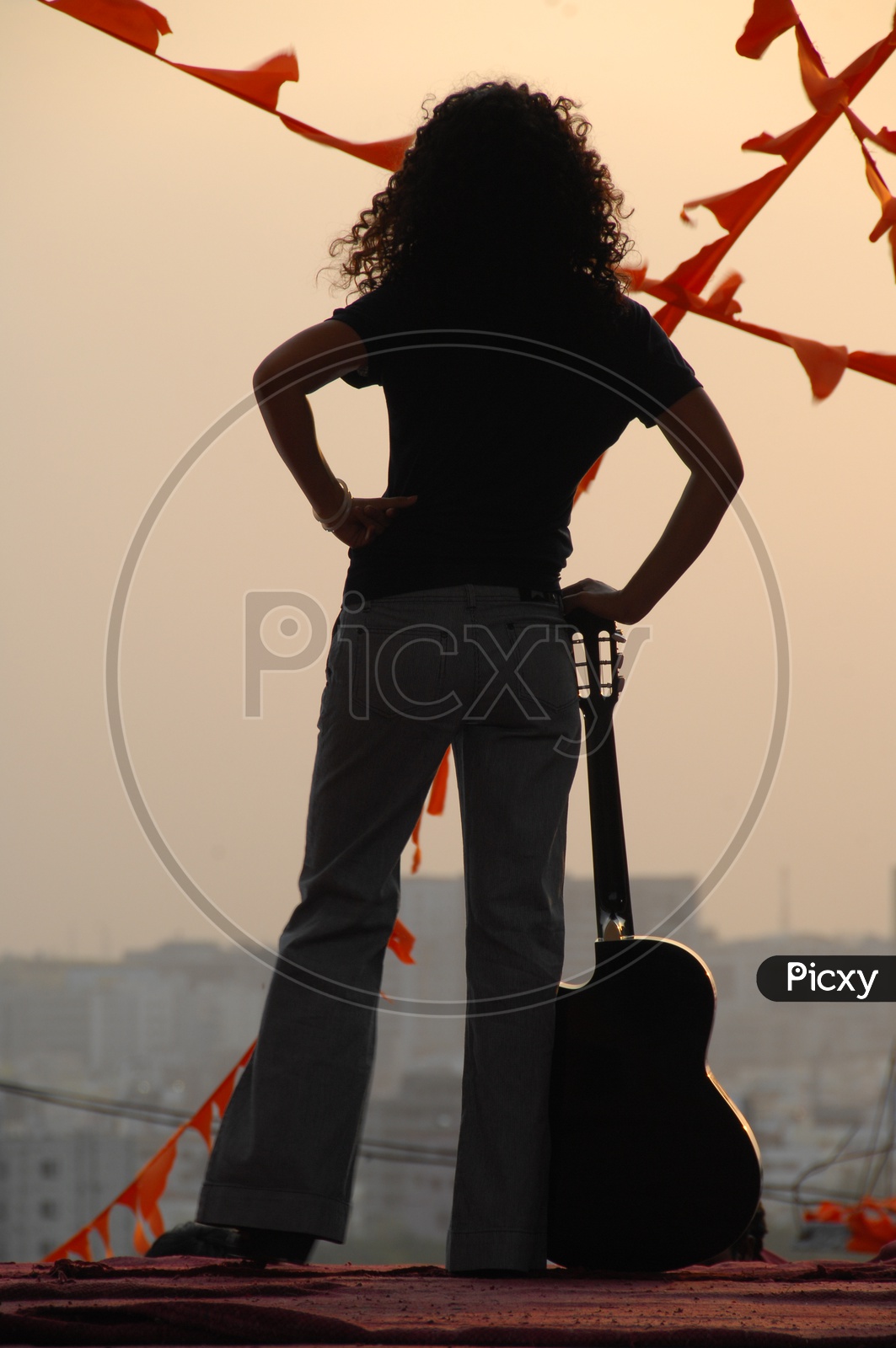 Silhouette of Woman Enjoying Evening Sunshine With a Guitar