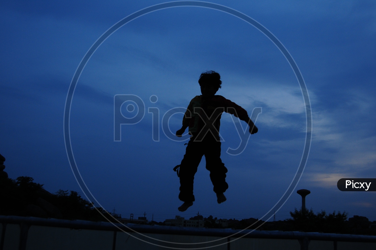 Silhouette Of a Boy Jumping in Joy Over Blue Hour Sunset Sky