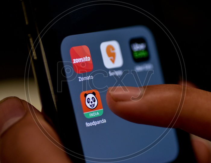 Man Finger Opening An Online Food Ordering Or Delivering App Icons On a Smartphone Screen With Selective Focus on Food Panda