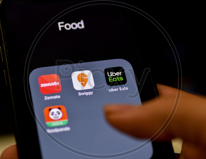 Man Finger Opening An Online Food Ordering Or Delivering App Icons On a Smartphone Screen With Selective Focus