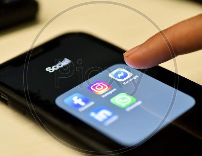 Social Network Apps On a Smartphone Screen Closeup With Man Finger On Facebook Messenger Icon