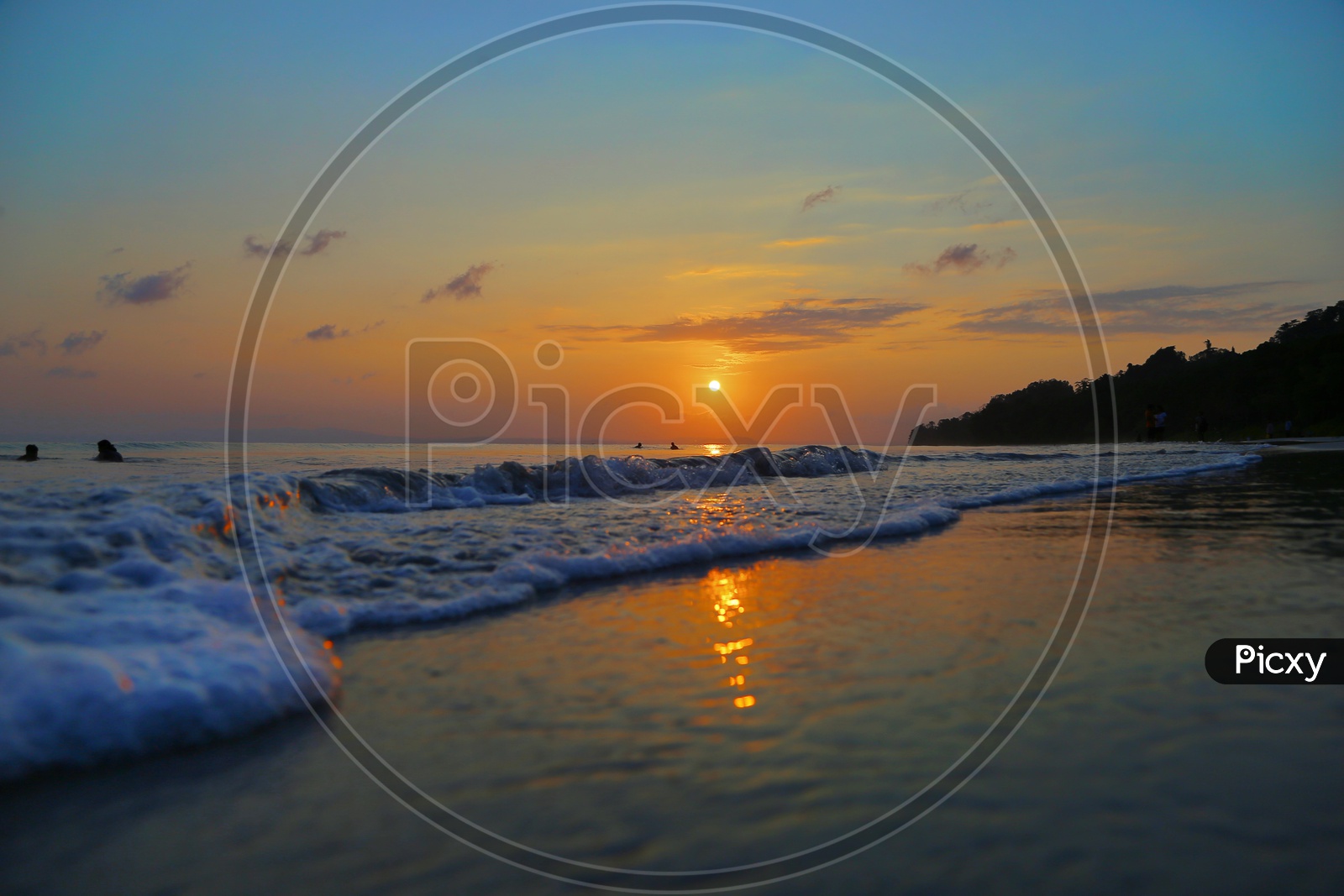 Sunset Over A Beach With Sea Waves Striking The Beach