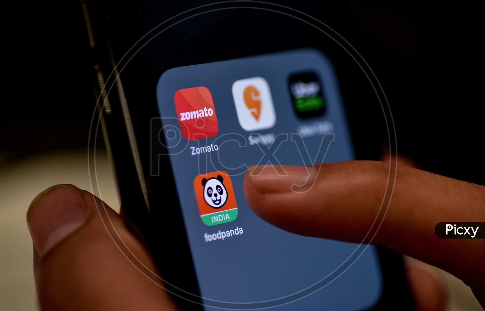 Man Finger Opening An Online Food Ordering Or Delivering App Icons On a Smartphone Screen With Selective Focus on Food Panda