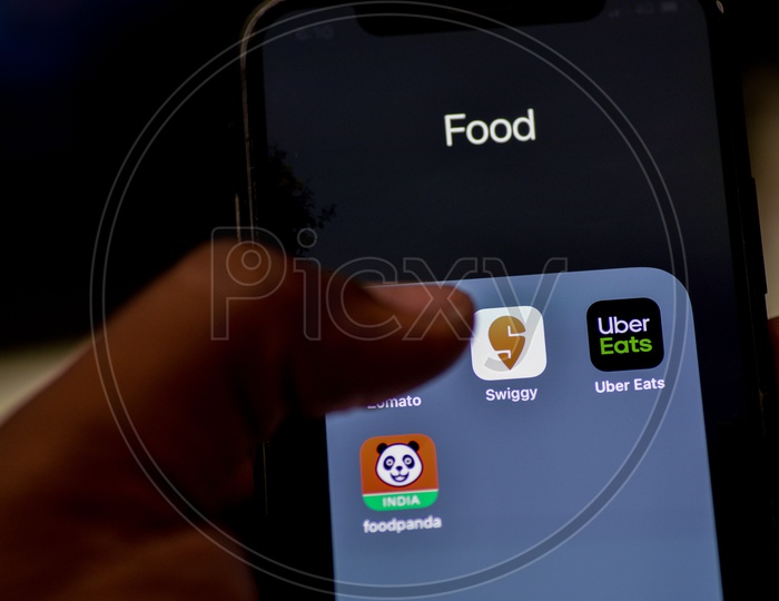 Man Finger Opening An Online Food Ordering Or Delivering App Icons On a Smartphone Screen With Selective Focus on Swiggy