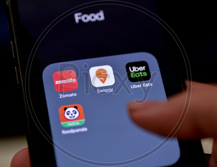 Man Finger Opening An Online Food Ordering Or Delivering App Icons On a Smartphone Screen With Selective Focus