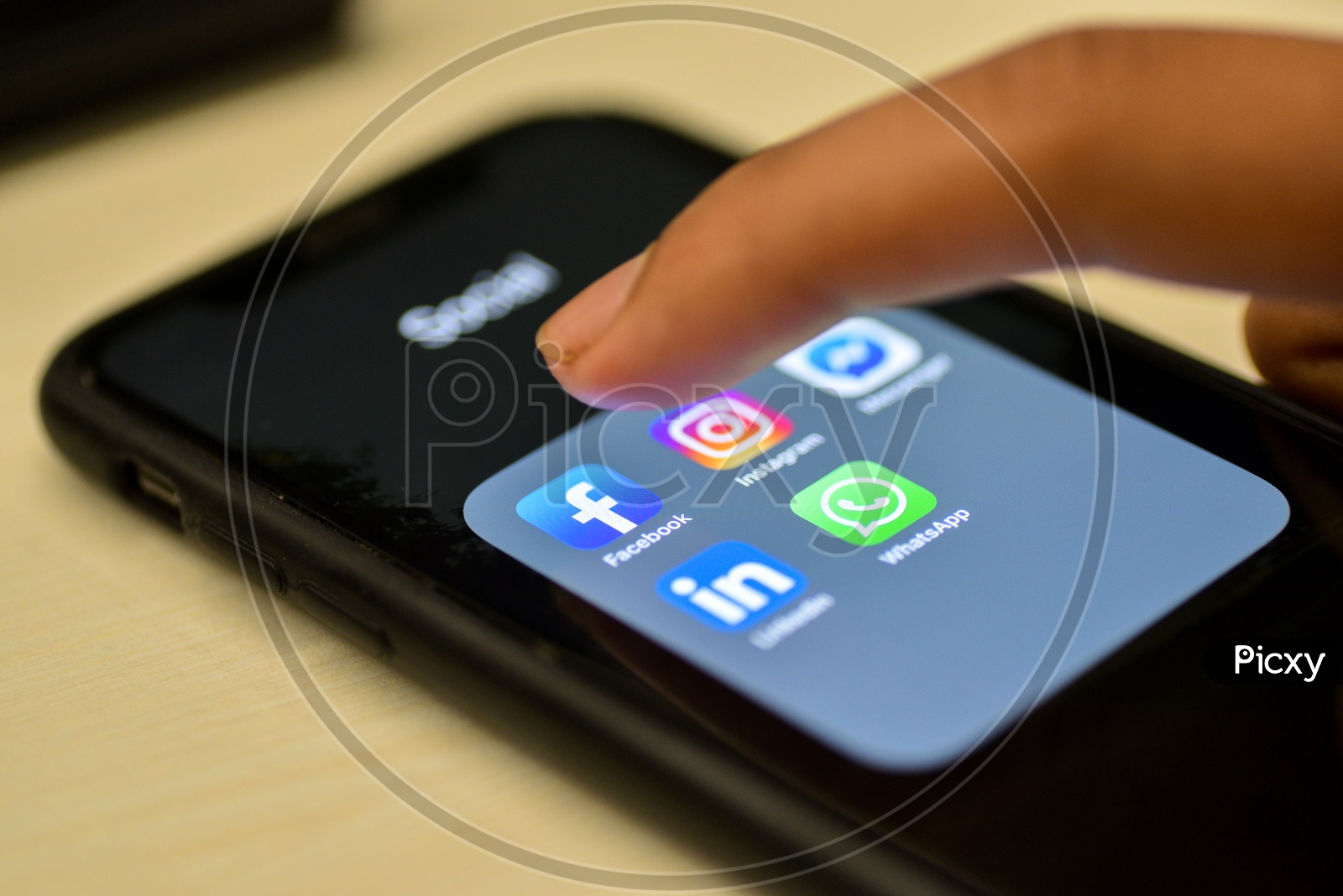 Social Network Apps On a Smartphone Screen Closeup With Man Finger On Facebook Icon