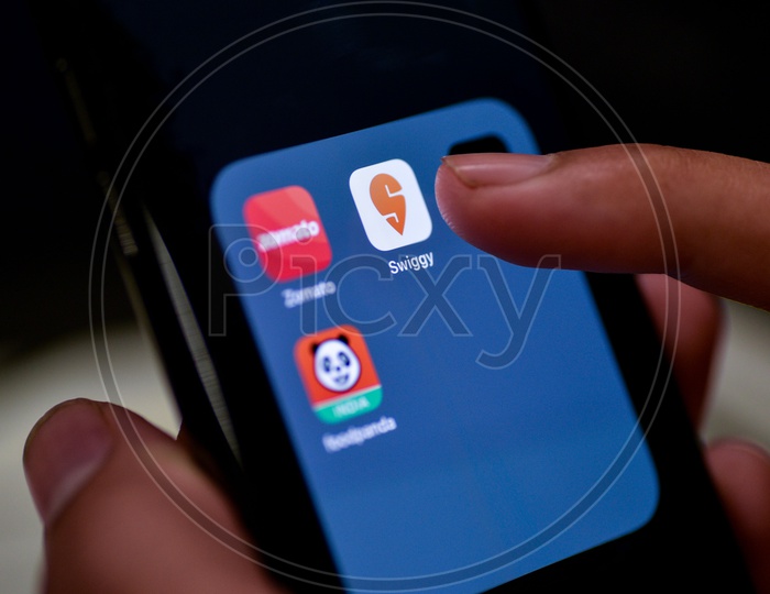 Man Finger Opening An Online Food Ordering Or Delivering App Icons On a Smartphone Screen With Selective Focus on Swiggy