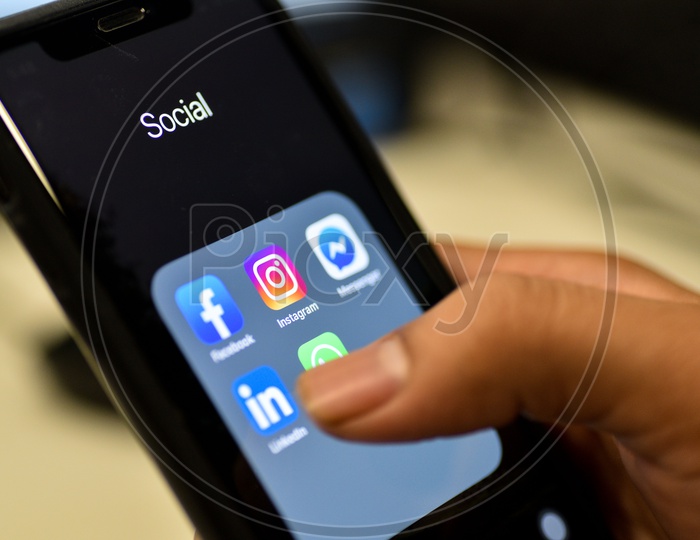 Social Networking Apps Installed In a Smartphone Icons Closeup With Man Finger Opening Linkedin App