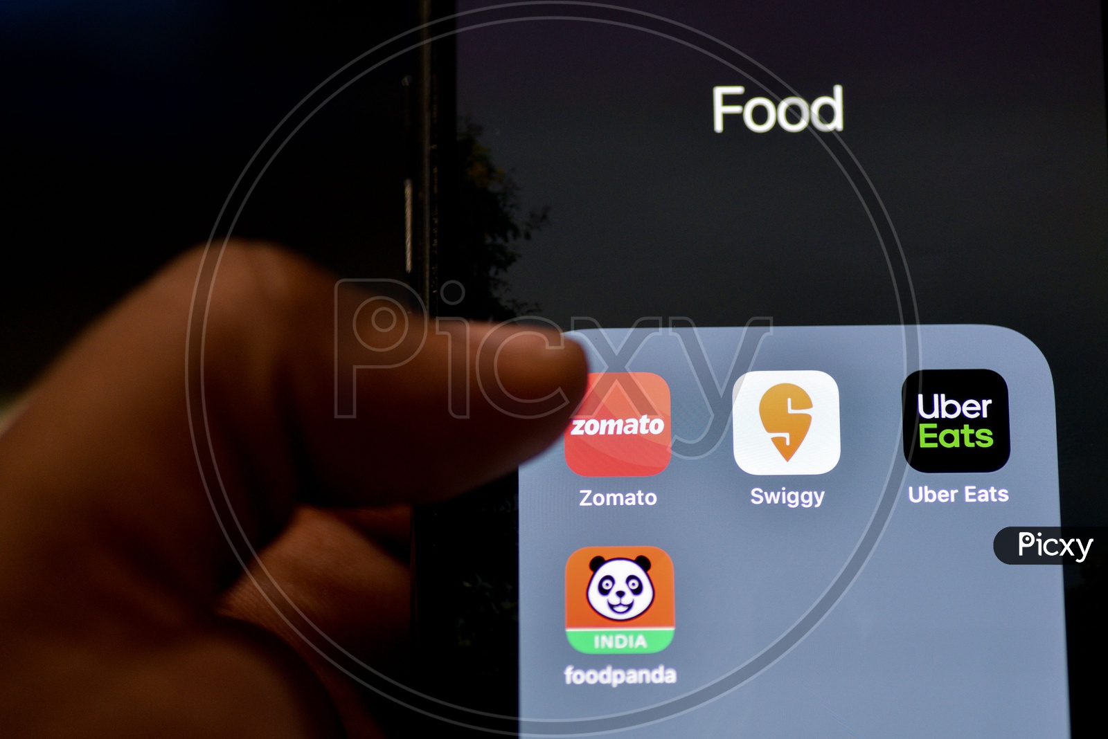 Man Finger Opening An Online Food Ordering Or Delivering App Icons On a Smartphone Screen With Selective Focus on Zomato