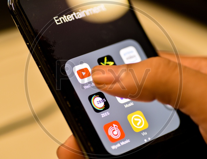 Entertainment Online Streaming Apps Installed Icons  On a Smartphone Screen Closeup With Man Finger Opening Youtube App