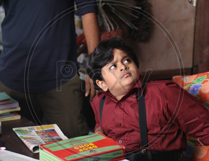 Young Boy Siting At a Shop Cash Counter And Looking Seriously