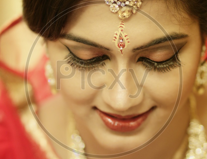 Stunning Indian Bride Dressed In Hindu Red Traditional Wedding Clothes Sari Embroidered With Gold Jewelry And A Veil Smiles Tender With Extra Copy Space.