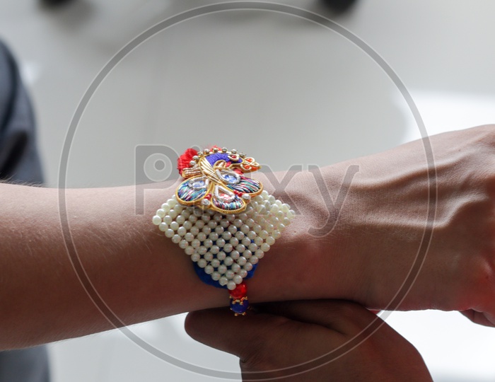 Hand Of A Lady Tying Rakhi In Hand Of A Guy During The Hindu Ritual Of Rakshabandhan With Selective Focus