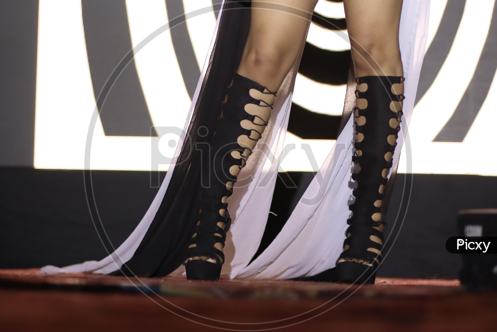feet of a dancer on stage doing hip hop dancing stance with background neon lights