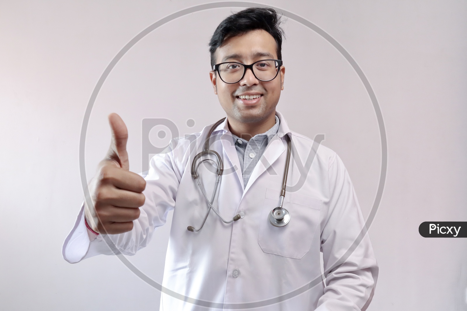 Male Indian Doctor In White Coat And Stethoscope Showing Thumbs Up In Confidence