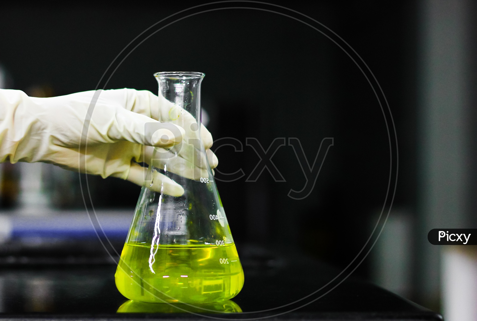 Scientist Holding A Glass Conical Flask In A Gloved Hand In Chemistry Laboratory