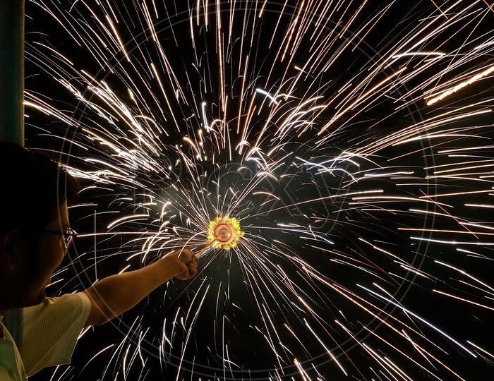 A Man Holding Hand Charki, A Hand Firework Emitting Circular Sparks In Black Background
