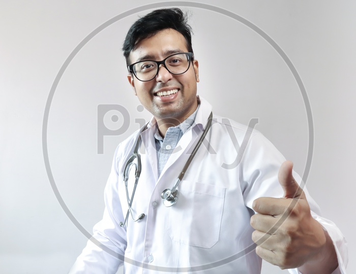 Male Indian Doctor In White Coat And Stethoscope Showing Thumbs Up With Smart Phone