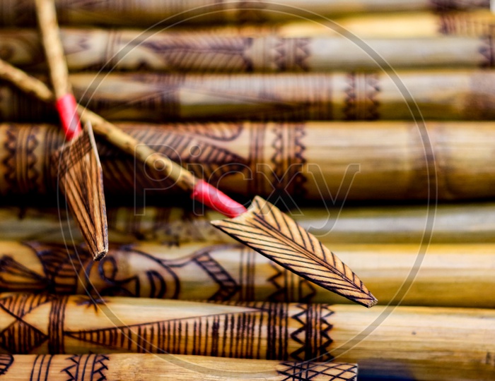 Arrow Showing Hand Made Wooden Bamboo Carving Engraved Fish Figure Artwork On Bamboo, Rows Of Engraved Bamboo Sticks. Tribal Artwork. Textured Background