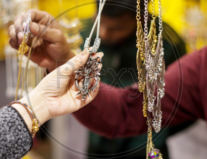 Hand Of A Lady Selecting Necklace Chain Metal Junk Jewellery At A Shop.