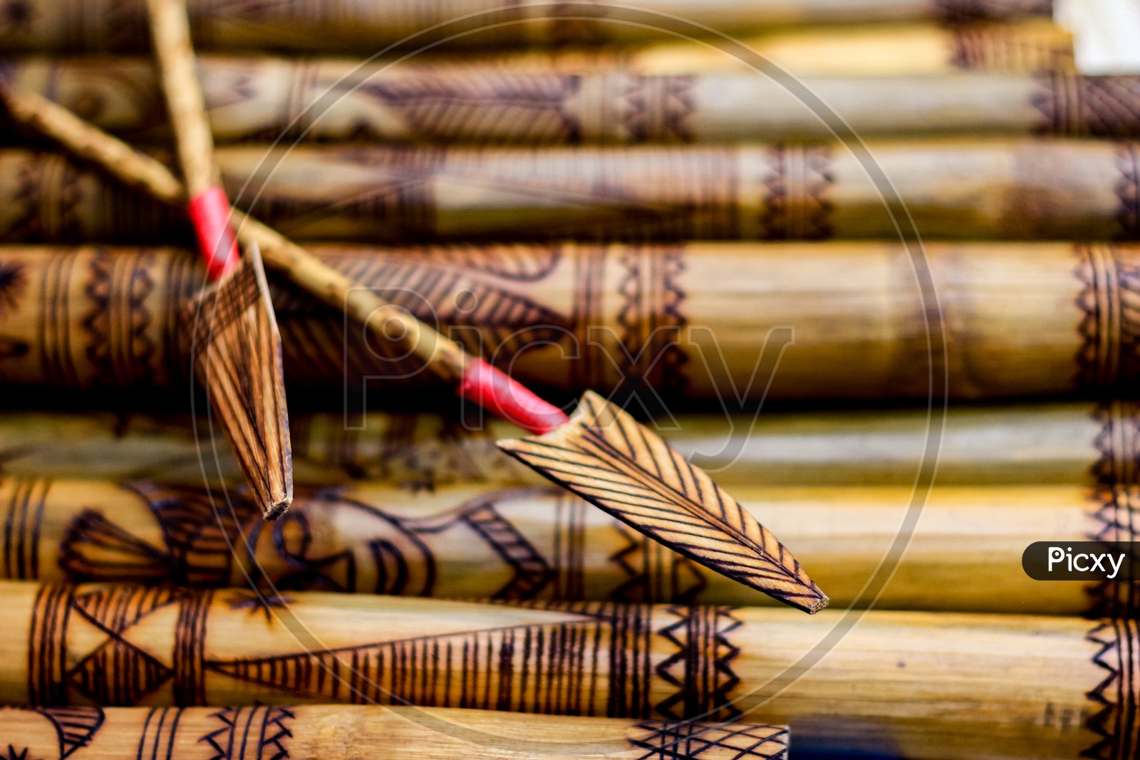 Arrow Showing Hand Made Wooden Bamboo Carving Engraved Fish Figure Artwork On Bamboo, Rows Of Engraved Bamboo Sticks. Tribal Artwork. Textured Background