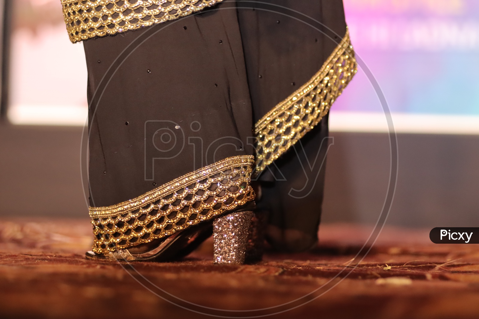 Feet Closeup Of a Woman Wearing Saree  Walking On Stage With Heel Sandal Footwear And Neon Lights