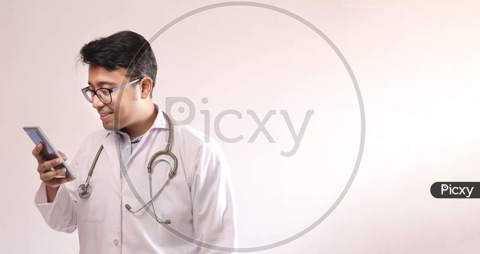 Male Indian Doctor In White Coat And Stethoscope Touching Smart Phone
